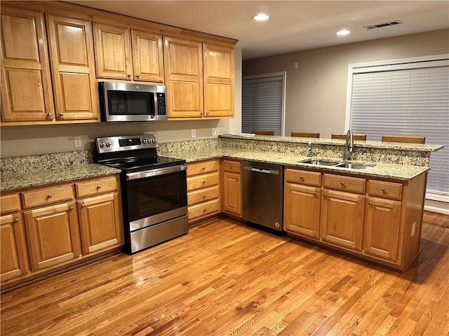 kitchen with light stone counters, sink, kitchen peninsula, and stainless steel appliances