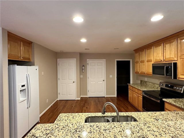 kitchen featuring dark hardwood / wood-style floors, light stone countertops, sink, and appliances with stainless steel finishes