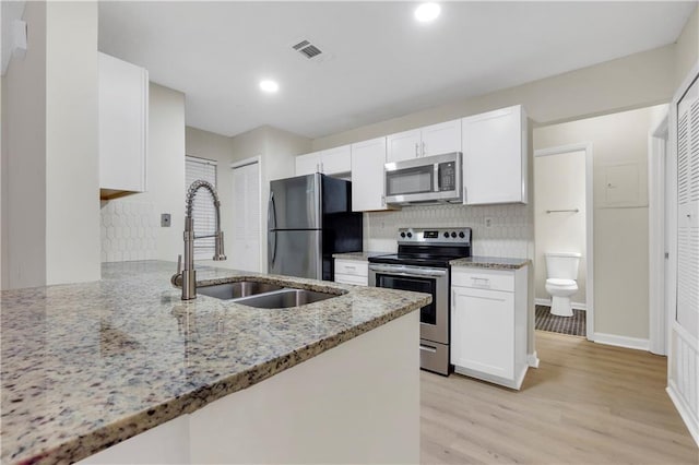 404 Hawkstone Way, Alpharetta, GA 30022 - kitchen with appliances with stainless steel finishes, white cabinetry, decorative backsplash, light stone counters, and light wood-type flooring