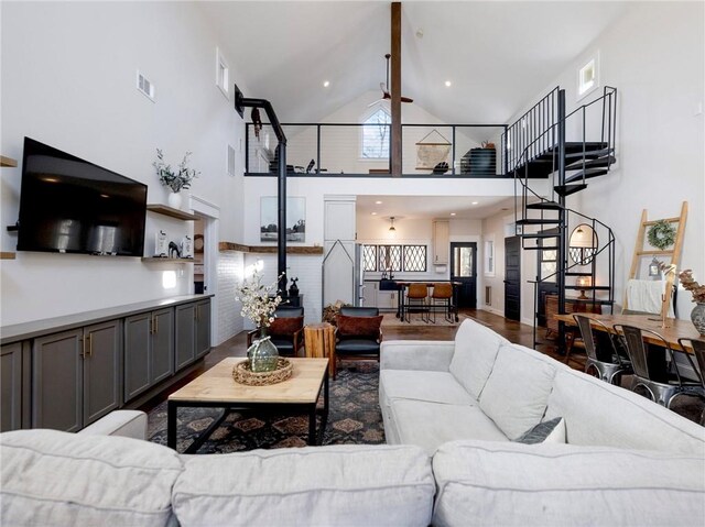 living area featuring visible vents, a ceiling fan, wood finished floors, stairs, and high vaulted ceiling