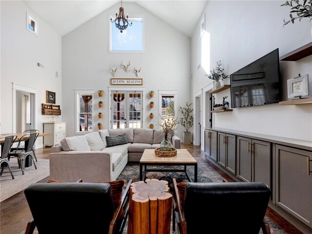 living room with a chandelier, dark wood finished floors, visible vents, and vaulted ceiling