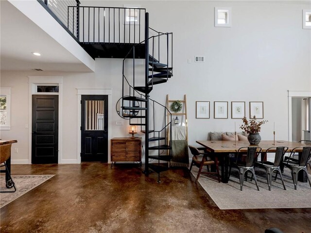 dining space with visible vents, stairway, a towering ceiling, finished concrete floors, and baseboards