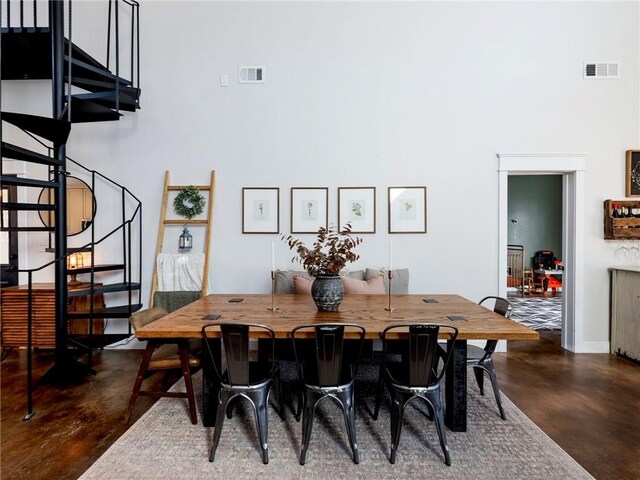 dining room featuring stairs, concrete floors, a towering ceiling, and visible vents