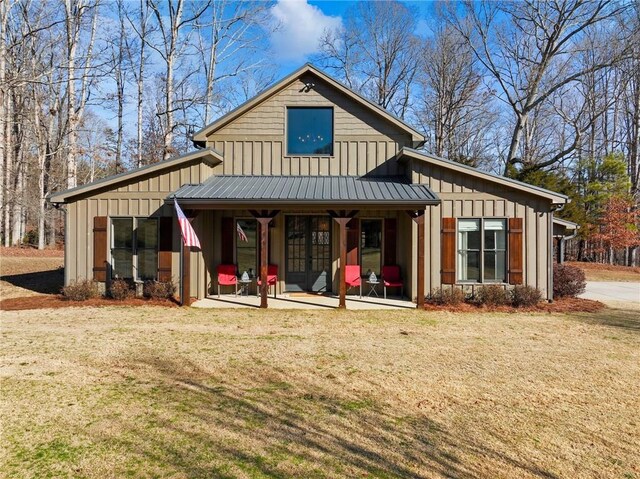 rear view of property featuring metal roof, board and batten siding, and a yard