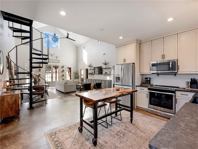 kitchen with stainless steel appliances, dark countertops, high vaulted ceiling, and recessed lighting