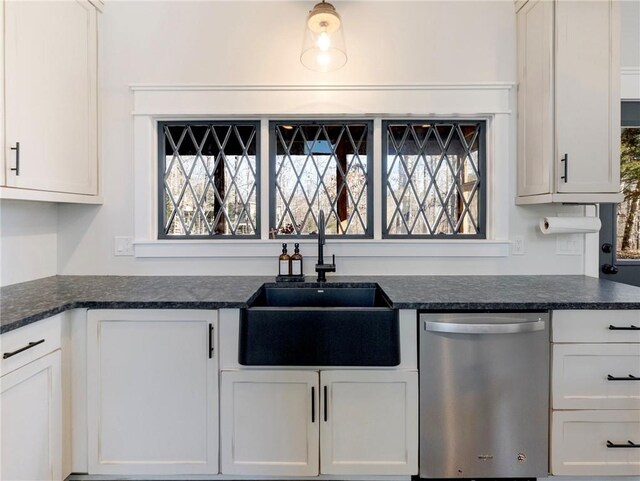 kitchen featuring dark stone countertops, white cabinets, a sink, and stainless steel dishwasher