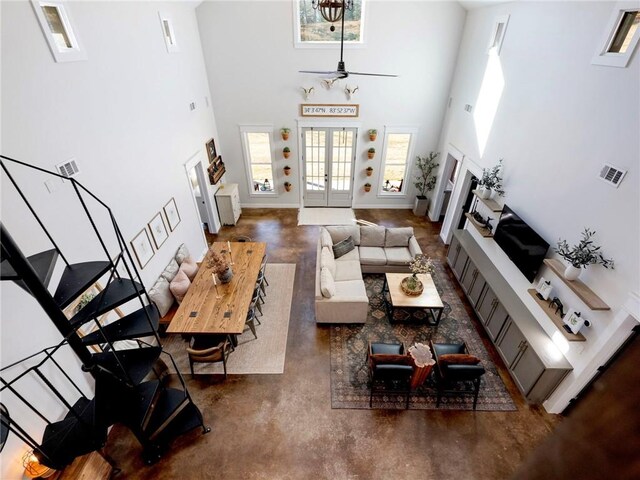 living room featuring visible vents, a towering ceiling, finished concrete floors, french doors, and a fireplace