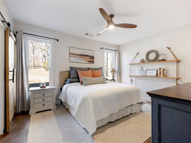 bedroom with visible vents, ceiling fan, and a barn door