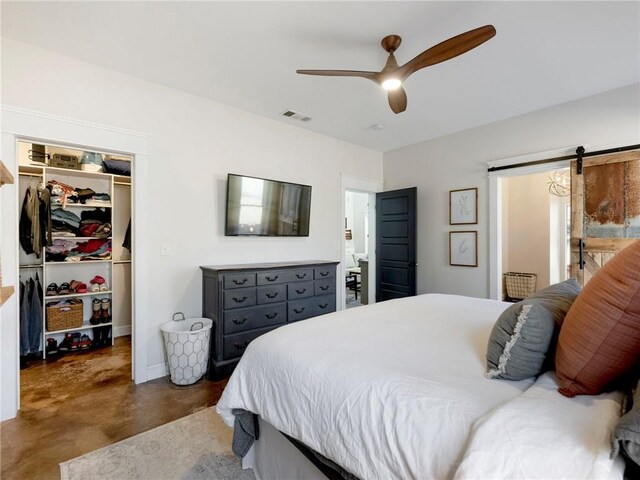 bedroom featuring finished concrete flooring, a barn door, visible vents, a spacious closet, and a closet