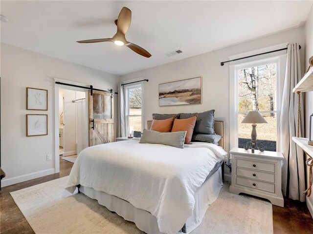 bedroom with ceiling fan, a barn door, visible vents, and baseboards