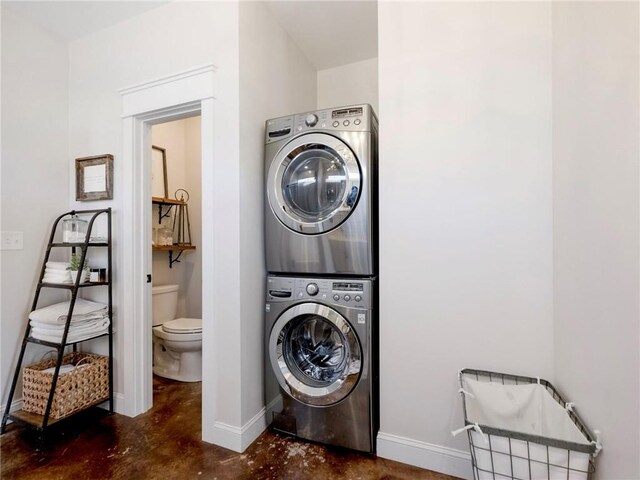 washroom featuring stacked washing maching and dryer, baseboards, and laundry area