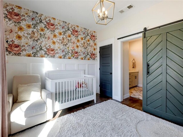 bedroom featuring wallpapered walls, a barn door, visible vents, a wainscoted wall, and a decorative wall