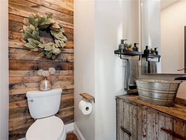 half bathroom featuring toilet, baseboards, and vanity