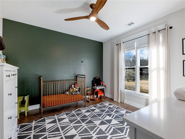 bedroom featuring a ceiling fan, wood finished floors, visible vents, and baseboards