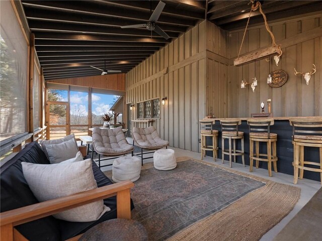 living room featuring a dry bar, wooden walls, a ceiling fan, lofted ceiling, and a sunroom