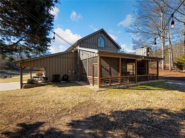 exterior space with a lawn, board and batten siding, and a sunroom