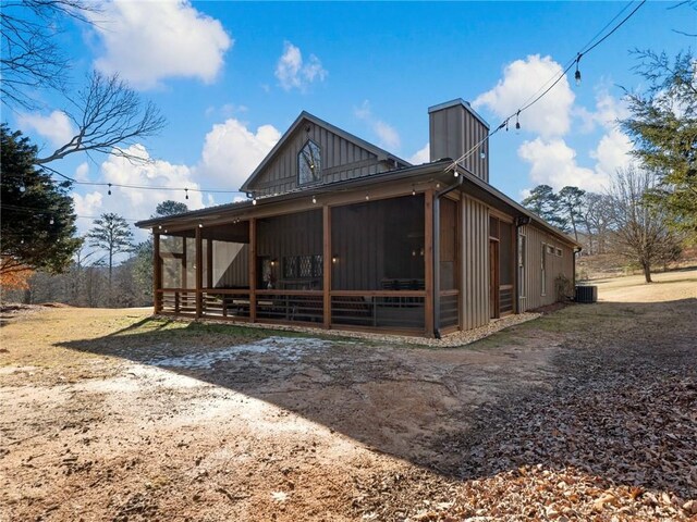 back of property with board and batten siding and a sunroom