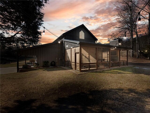 exterior space featuring a sunroom, a lawn, and board and batten siding