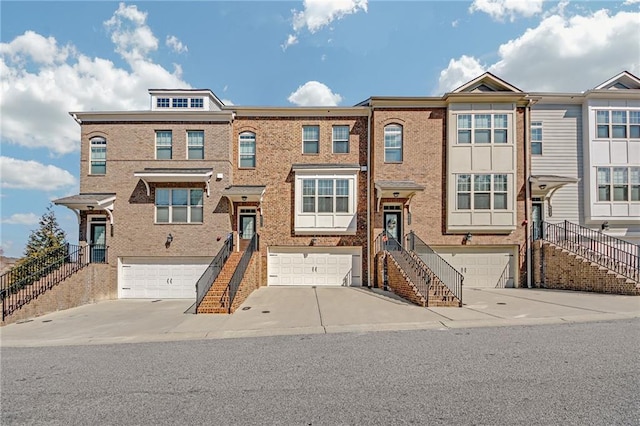 view of property featuring stairs, driveway, brick siding, and a garage