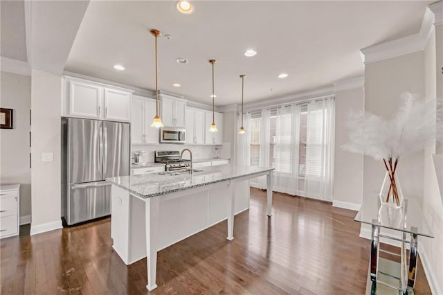 kitchen featuring decorative light fixtures, a center island with sink, stainless steel appliances, white cabinets, and a sink