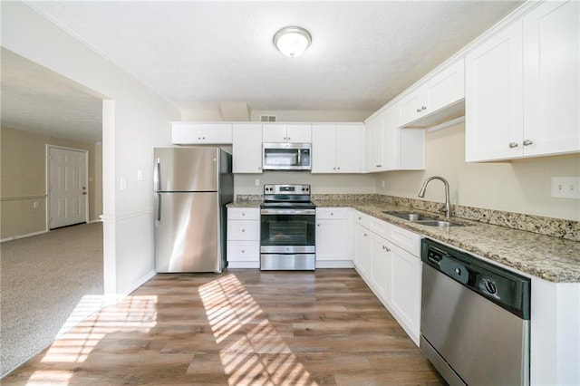 1129 Winston Dr, Decatur, GA 30032 - kitchen with appliances with stainless steel finishes, dark hardwood / wood-style flooring, light stone countertops, white cabinets, and sink