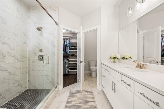 full bath with a walk in closet, marble finish floor, a shower stall, and vanity