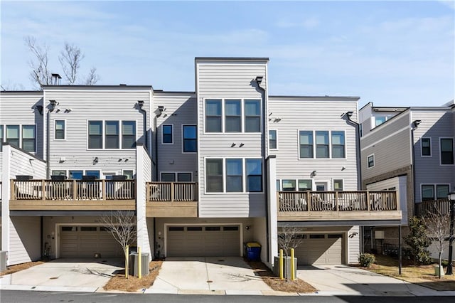 rear view of property with a garage, driveway, and central AC unit