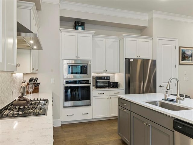 kitchen with sink, white cabinetry, light stone counters, extractor fan, and appliances with stainless steel finishes