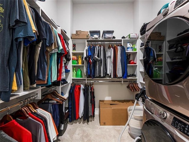 spacious closet featuring stacked washer and dryer and light carpet