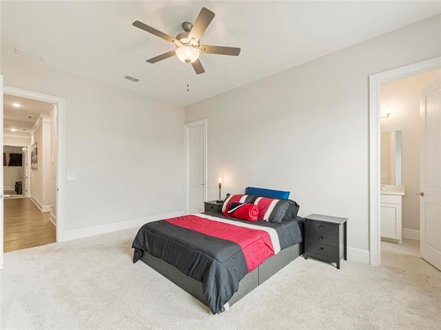 carpeted bedroom with ensuite bath and ceiling fan