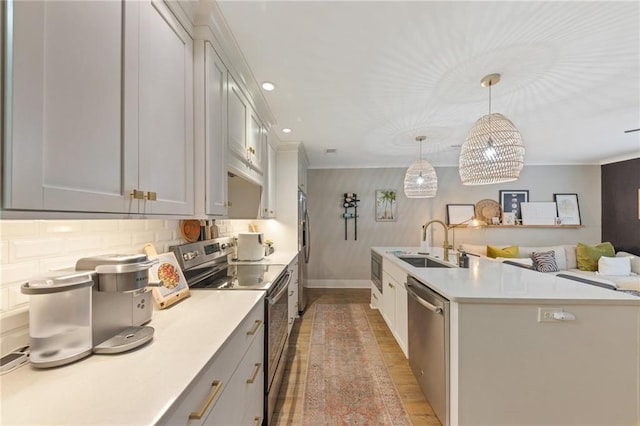 kitchen with sink, wood-type flooring, hanging light fixtures, stainless steel appliances, and backsplash