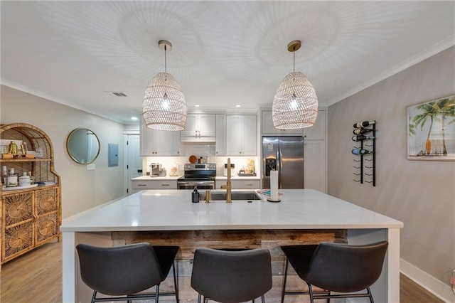 kitchen with hanging light fixtures, appliances with stainless steel finishes, sink, and a breakfast bar