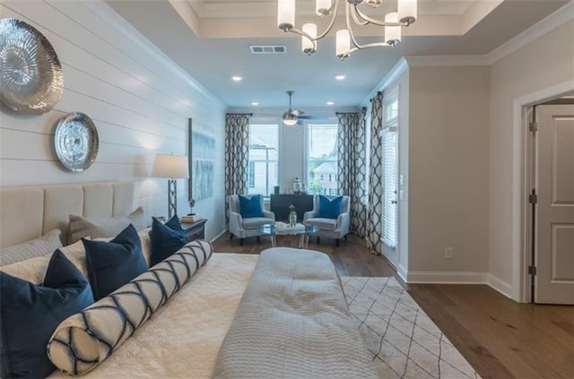 interior space with a tray ceiling, wood-type flooring, a chandelier, and ornamental molding