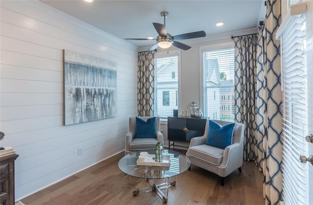 living area featuring ceiling fan, wooden walls, and dark hardwood / wood-style flooring