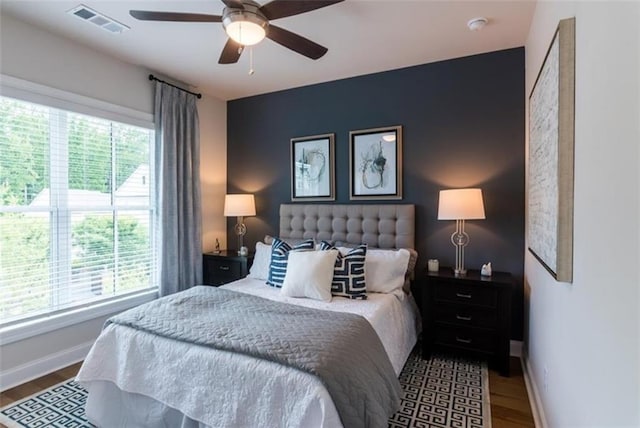 bedroom with dark wood-type flooring, multiple windows, and ceiling fan