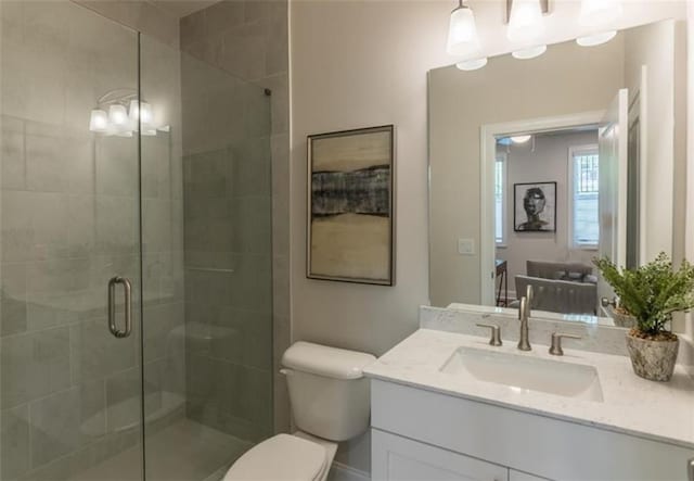 bathroom featuring vanity, toilet, and a shower with door