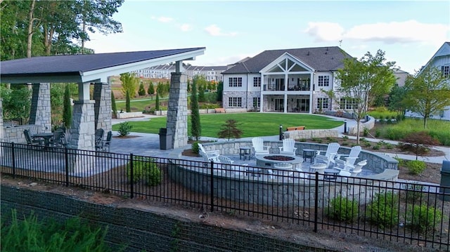 view of property's community featuring a lawn, a patio, and a fire pit