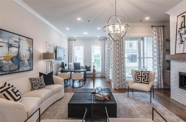 living room with crown molding, a notable chandelier, a brick fireplace, and hardwood / wood-style flooring