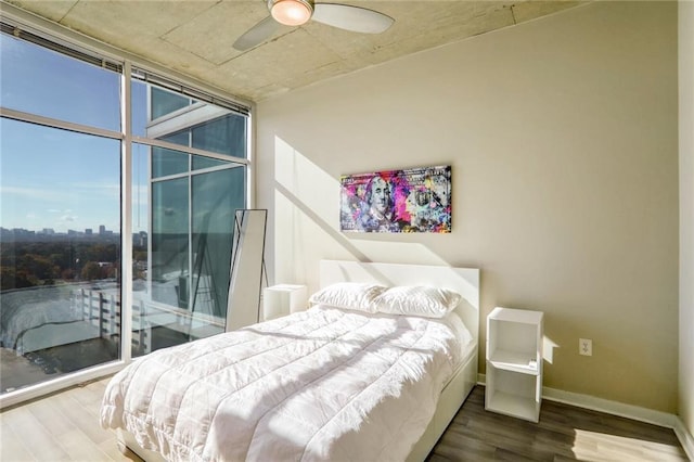 bedroom featuring wood finished floors, a wall of windows, and baseboards