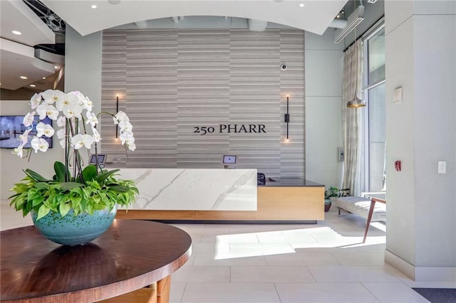 reception with a high ceiling, tile walls, and recessed lighting