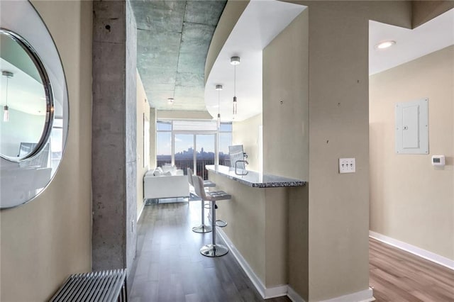 corridor with wood finished floors, baseboards, and electric panel