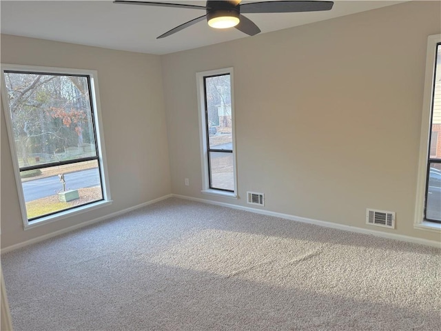 spare room with carpet floors, a wealth of natural light, and ceiling fan