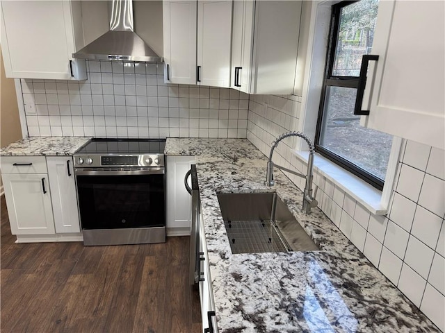 kitchen with wall chimney exhaust hood, stainless steel electric range, and white cabinets