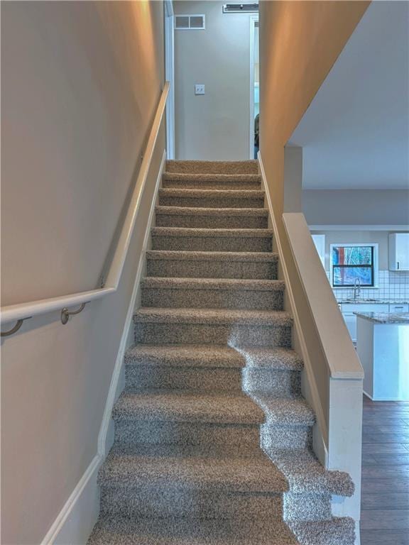 stairs featuring sink and hardwood / wood-style floors