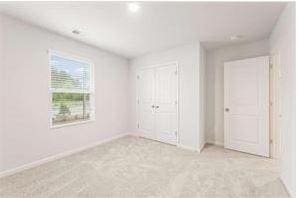 unfurnished bedroom featuring light colored carpet and a closet