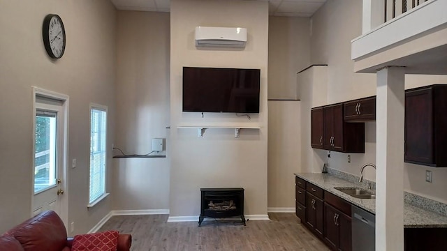 kitchen featuring a wall unit AC, sink, stainless steel dishwasher, and dark brown cabinets