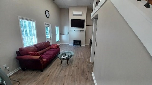 living room with hardwood / wood-style floors, a towering ceiling, and a wall mounted AC