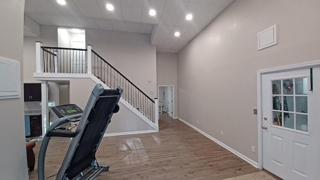 interior space with a drop ceiling, a towering ceiling, and hardwood / wood-style flooring