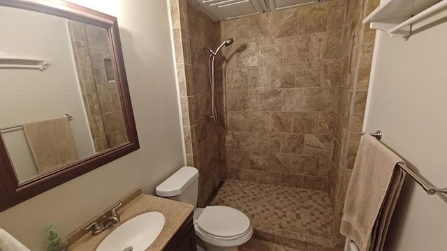 bathroom with a tile shower, vanity, and toilet