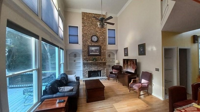 living room featuring ceiling fan, built in features, a towering ceiling, and ornamental molding